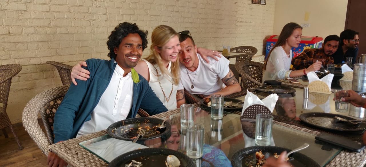 International and Indian yoga teacher-training students share a sattvic meal together, laughing around the table at Yoga Bhawna Mission.